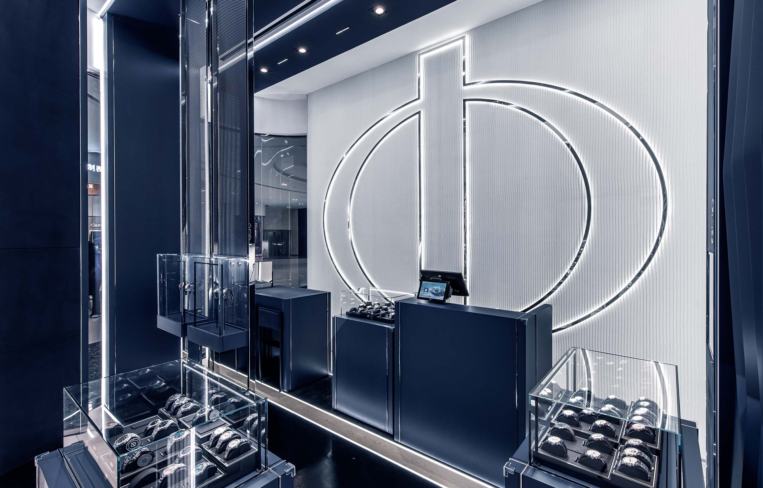 Pop-Up Boutique-Konzept Uhrenladen. Ansicht Uhrenvitrinen und Counter - Logo hinterleuchtet. Baume & Mercier - MACH Architektur.